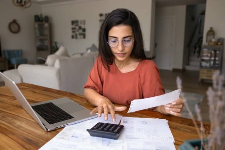 Vrouw analyseert financiële documenten thuis voor tandartskosten 2025.