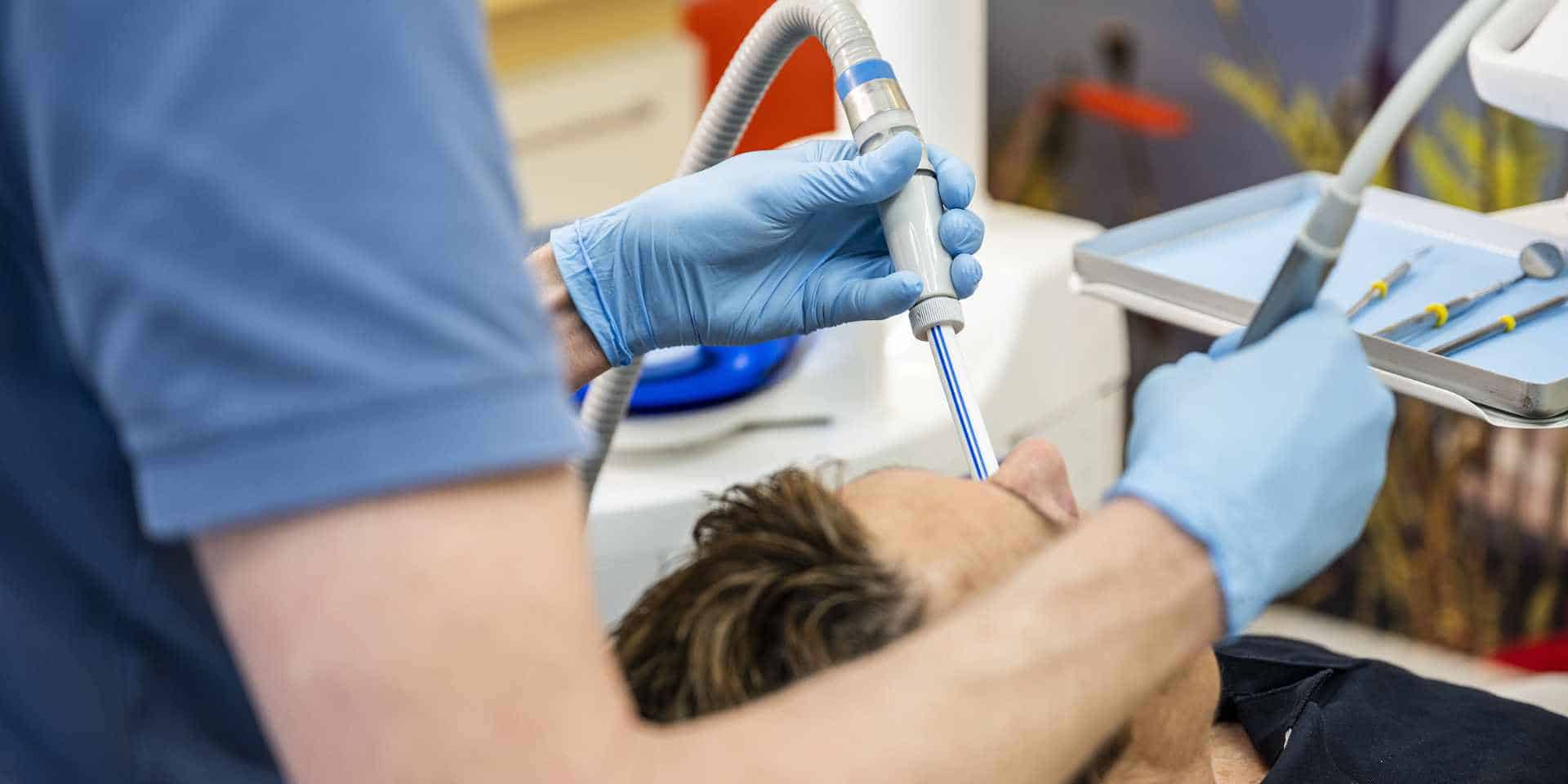 Tandarts voert tandheelkundige behandeling uit bij patiënt.